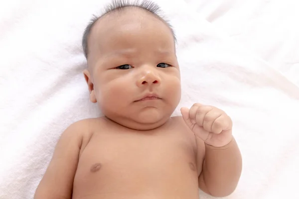 A newborn baby is lying on a white mattress