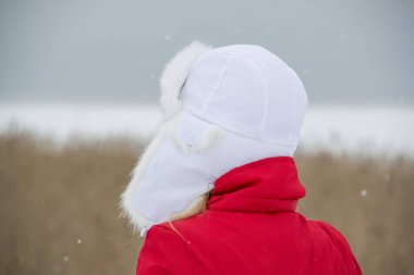 Kışın açık havada Beyaz Şapkalı ve Kırmızı Ceketli Kadın