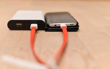 Siyah bir bezelyesiz akıllı telefonu güç bankasıyla şarj etmek.