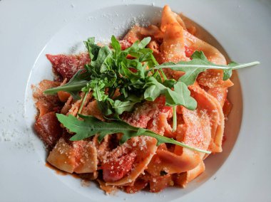 Beyaz tabakta sebzeli somon makarnası.