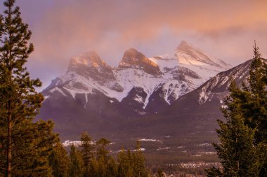 Beauty of Bow Valley mountains, Canmore, Canada, sunset light and storm above Three sisters peak, in the fog, flurries in mountains clipart
