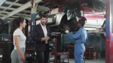 Kadın müşteri ve Latin erkek müdür, Siyah Mekanik Kadın, araba süspansiyonu ve sigortalı garantisi, otomotiv garajında müşteri hizmetleri bakımı ve ulaşım endüstrisi konularını görüştü..