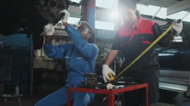 İki kadın tamirci tartışıyor, Latin ve Siyah işçiler otomotiv tekerleklerini tamir ediyor ve garaj istasyonunda araba süspansiyonlarını koruyor, ve araç taşımacılığı sektöründe teknisyen mühendisliği hizmeti veriyor.