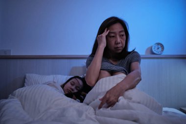 Asyalı bekar anne uykusuz, stresli ve kızının yanında boşandıktan sonra geceleri endişeli, uykusuzluk hastalığı yatak odasında, olgun ve menopozlu kadın, aile sağlık sorunu, yaşam tarzı.