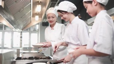 Beyaz kadın usta şef, stajyer öğrencilere, restoran mutfağında pilav pişirme, leziz yemeklerde profesyonel gurme, malzeme hazırlama ve aşçılık yemekleri öğretiyor..