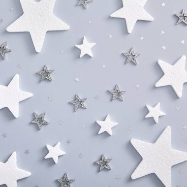 Noel en az desen - beyaz ve gümüş yıldızlı monokrom düzeni. Kare kompozisyon, düz döşeme, üst manzara. Klasik tatil dekoru.