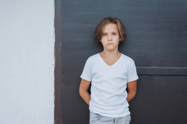 Siyah beyaz arka planda uzun saçlı şık bir çocuk.