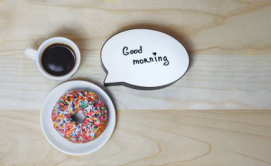 Bir fincan kahveyle donut ve ahşap desenli bir tabak. Konu açılmışken Günaydın..