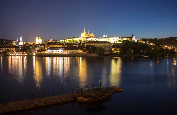 stock image Pargue charles bridge and prague castle by night reflections river with boat motive in the front