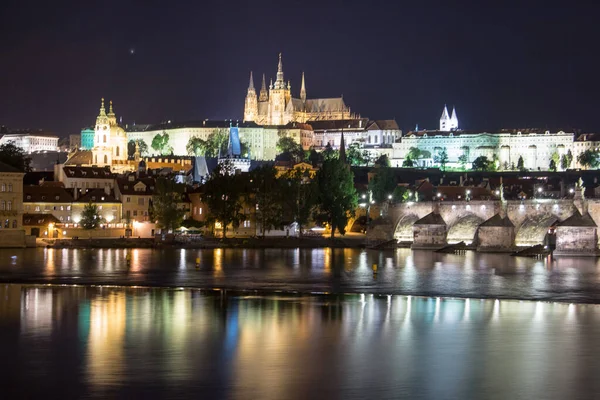 Pargue Charles bridge and prague castle by night reflections river — стоковое фото