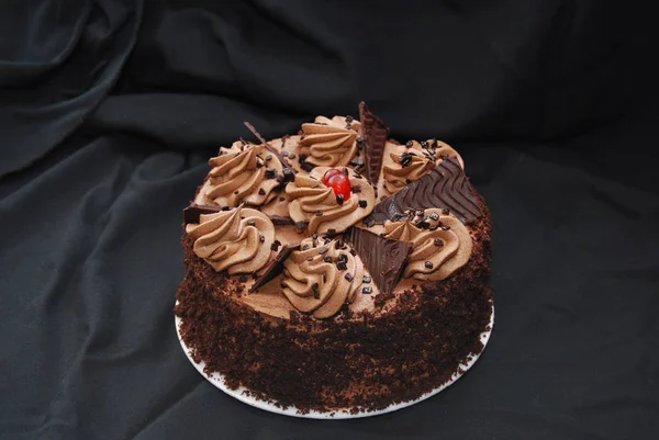Chocolate layer cake with frosting and cherry
