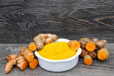 Taze Tumeric Kökü, bir bütün ve bir çanak toz karın ağrısı ile kırsal ahşap arka planda kesilmiş.
