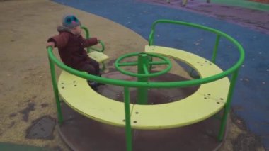 Küçük çocuk oyun parkında yeşil bir atlıkarıncada dönüyor.