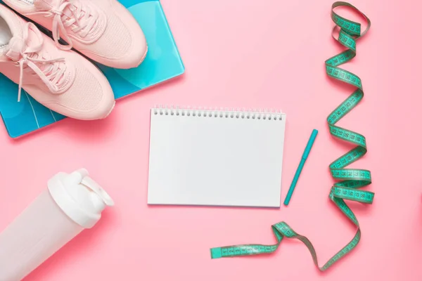 Atlet hazır. Spor aletleri - koşu ayakkabıları, teraziler, mezura ve pastel pembe arka planda protein plastik karıştırıcı. Kadın fitness egzersizi konsepti. Düz yatış, üst görünüm