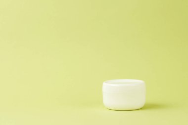 Beyaz kozmetik krem kapaklı. Yan görüş. Açık yeşil arka planda doğal bileşenleri olan organik cilt ürünleri. Çevre dostu güzellik endüstrisi konsepti. Boşluğu kopyala