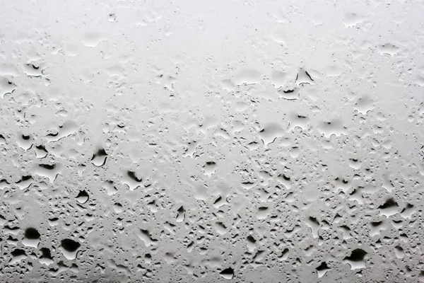 Mnoho kapek deště na okenní tabuli mimo šedou oblohu okna — Stock fotografie