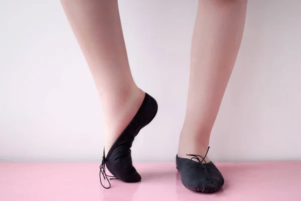 Nohy tanečnice v černých baletních botách dělají roztahovací vlak v pozici baletky — Stock fotografie