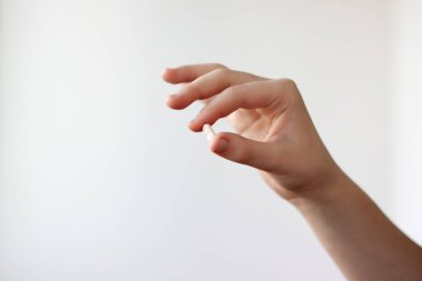 El beyaz arka planda açık pembe bir tablet tutuyor..