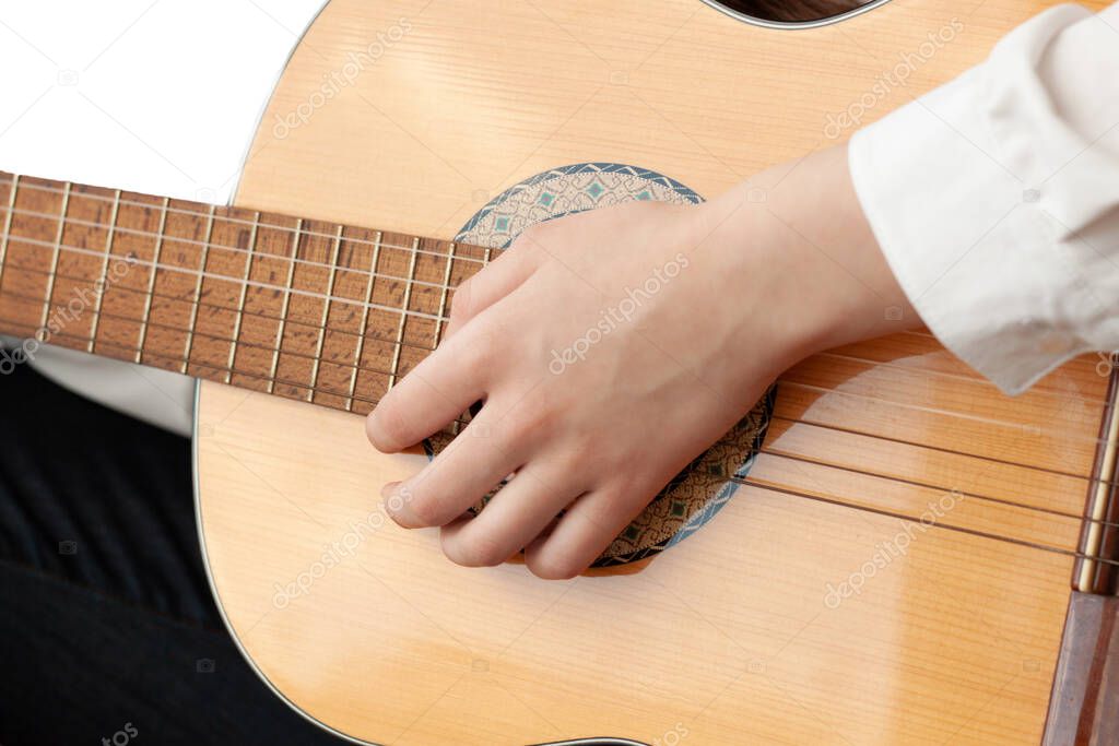 Close up of a girl's hand on the strings of a guitar.