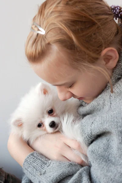 스웨터를 금발의 여자가 포메라니안 강아지를 강아지를 강아지를 안는다 — 스톡 사진