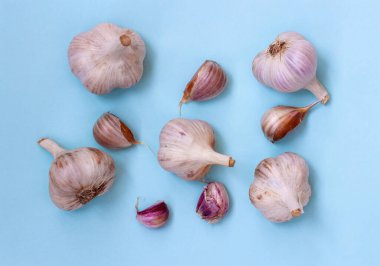 Mavi arka planda beş büyük sarımsak ve beş diş sarımsak var..