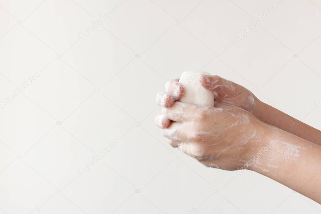 Two soapy hands clenched into fists holding soap on a white background. The concept of the need to wash hands to prevent diseases