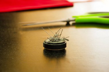 Bir masaüstünde dikiş atölyesinde mıknatıs üzerindeki metal iğneler. Küçük işletme kavramı