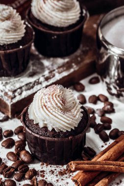 Kahve çekirdekleri ve tarçın arasındaki masada çikolatalı kek.