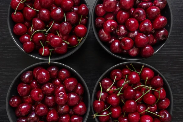 Due varietà di ciliegie si trovano in piatti scuri su uno sfondo scuro — Foto Stock