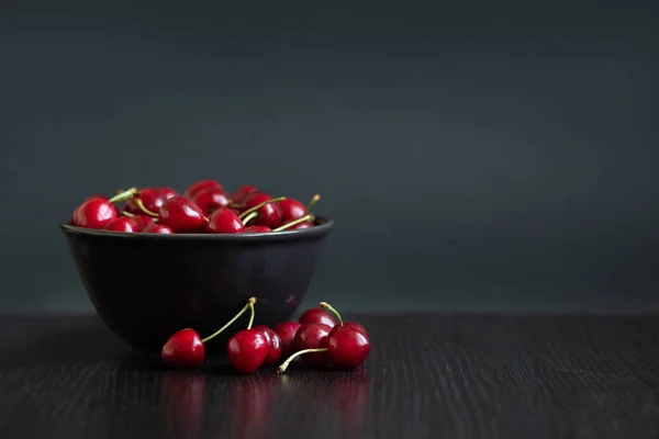 Ciliegia rossa con rametti primo piano su uno sfondo di un piatto scuro con ciliegie — Foto Stock