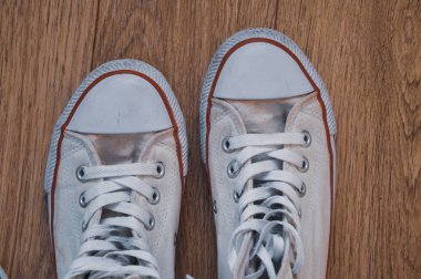 Ahşap zeminde eski beyaz spor ayakkabılar