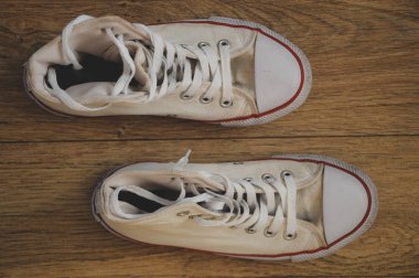 Ahşap zeminde eski beyaz spor ayakkabılar