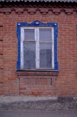 Antik ahşap beyaz pencere, mavi oymalı çerçeve ve öğleden sonra modern elementleri olmayan kırmızı tuğla duvar.
