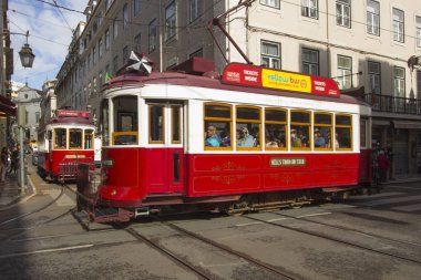 Lizbon dar sokaklarında sarayları arasında kırmızı bir tramvay