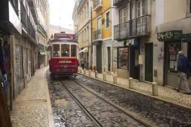 Lizbon dar sokaklarında sarayları arasında kırmızı bir tramvay