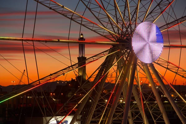 Ferris wheel in Genoa at sunset, in the background the lantern symbol of the city