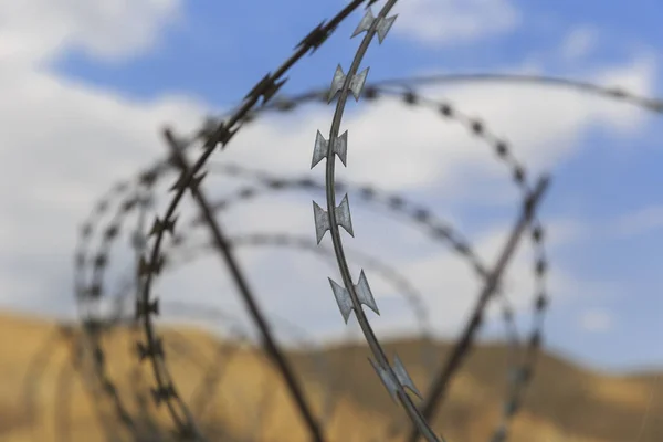 Barbed wire drawn in circles against a background of mountains — Stock Photo, Image