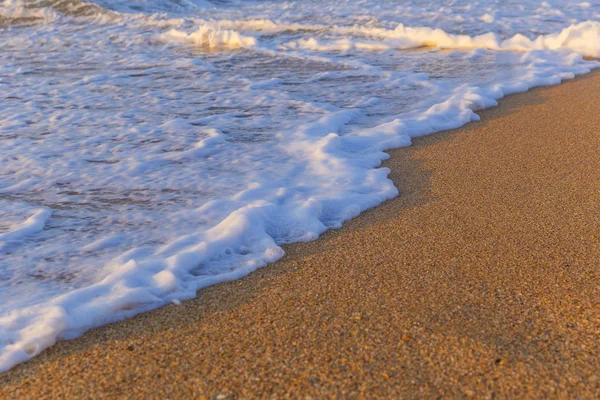 Piana z wody morskiej na wybrzeżu plaży w dniu zachodu słońca — Zdjęcie stockowe