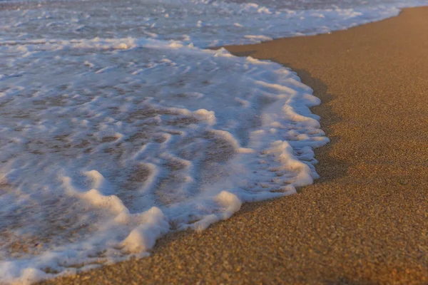 Пена из морской воды на побережье пляжа в день заката — стоковое фото