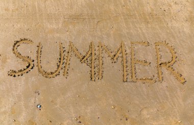 Yaz kelimesi kumsaldaki bir sopayla yazılmış.