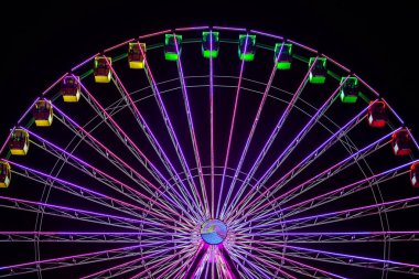 Güzel dönme dolap gece gökyüzünde bir panayırda neon ışıklarda parladı..