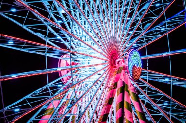 Güzel dönme dolap gece gökyüzünde bir panayırda neon ışıklarda parladı..