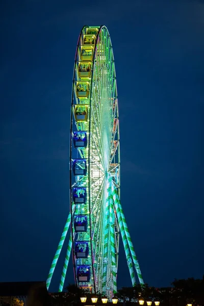 Beautiful Ferris Wheel lit up in neon lights in night sky at a fair.