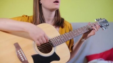 Akustik gitar çalan kız akorları öğreniyor.