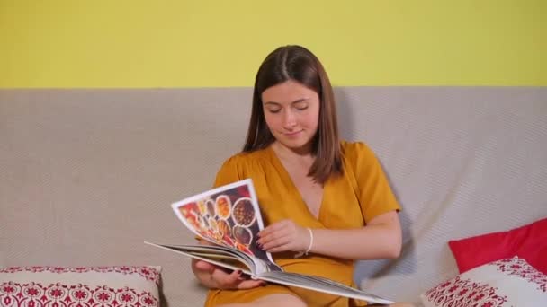 Девушка рассматривает книгу, листает страницы — стоковое видео