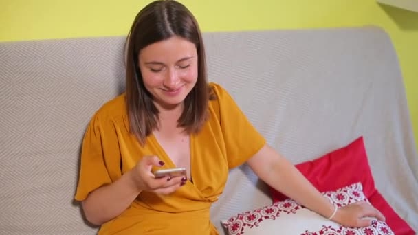Portret meisje lacht, maakt gebruik van smartphone, verlegen — Stockvideo