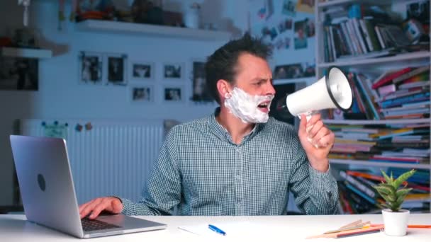 Office worker shouting into a megaphone, typing on laptop — Stock Video