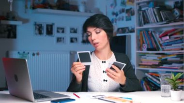 Kız masada oturuyor, polaroid resimlere bakıyor.