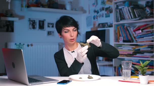 Ofisteki masada oturan kız bir kenevir tomurcuğunu parçalara ayırıyor. — Stok video