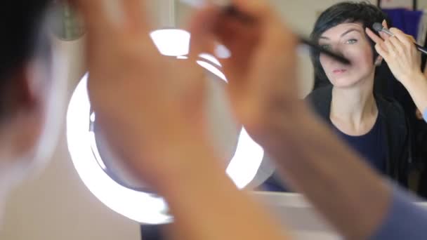 Portret meisje voor de spiegel met een borstel maakt make-up — Stockvideo